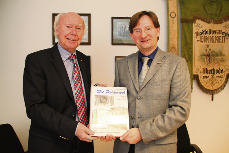 Feierliche Übergabe: Bezirksvorsteher Andreas Ege (rechts) überreicht seinem Vorgänger  Hinrich Baumann das erste Exemplar der zweiten Auflage des Buchs „Die Heidmark – Wandel einer Landschaft“.