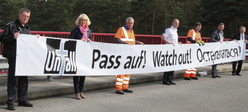 Mehrsprachig gewarnt: Vertreter von Polizei, Heidekreis und Straßenbauverwaltung präsentieren eines der  Hinweis-Banner, die an sechs Autobahnbrücken montiert wurden.