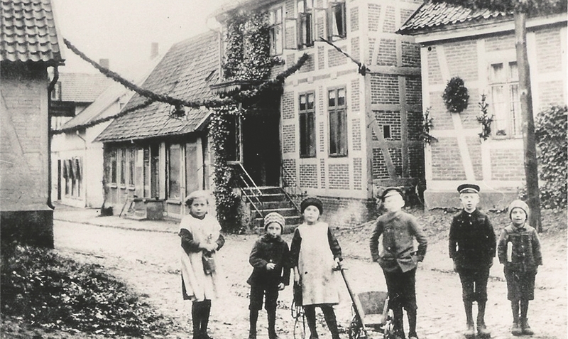Dorfmark anno dazumal: Blick in die Hauptstraße auf die Häuser von Uhrmacher Peter und der Sattlerei Vajen, 1919.ei(1)/red(5)