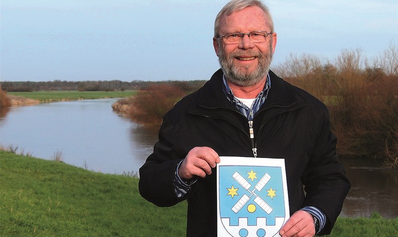 Bürgermeister Erich Lohse mit dem neuen Wappen der Gemeinde Gilten, im Hintergrund fließt die Leine. Foto: Matthias Kabel