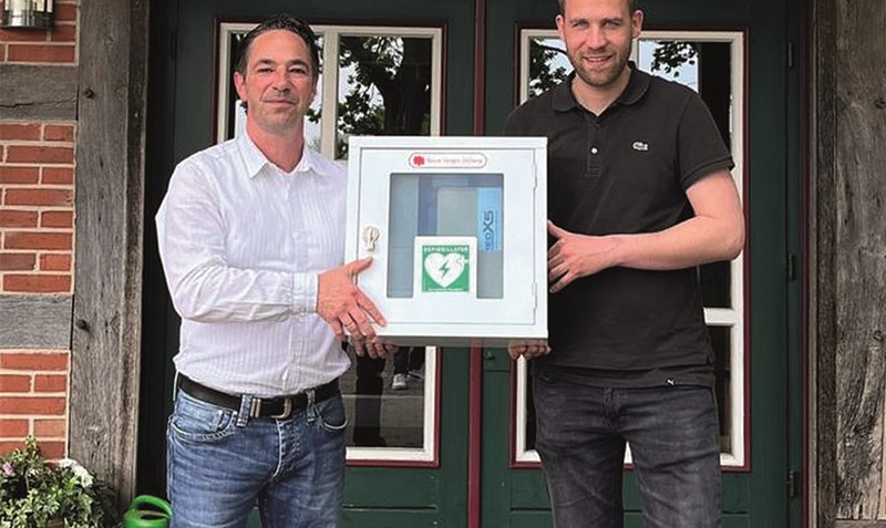 Defibrillator übergeben: Kai Schliekelmann (Bürgermeister Gemeinde Ahlden, links) und Hannes Luhmann (1. Vorsitzender TSV Ahlden, rechts). Foto: TSV Ahlden