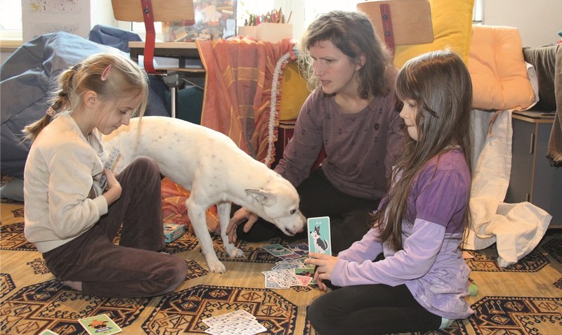 Da steckt auch Mathe drin: Beim entspannten Kartenspiel bringt die geschäftsführende Schulleiterin Sarah Quintern das Einmaleins ins Spiel, aufmerksam beäugt von Schulhund “Coffee”. Foto: Eickholt